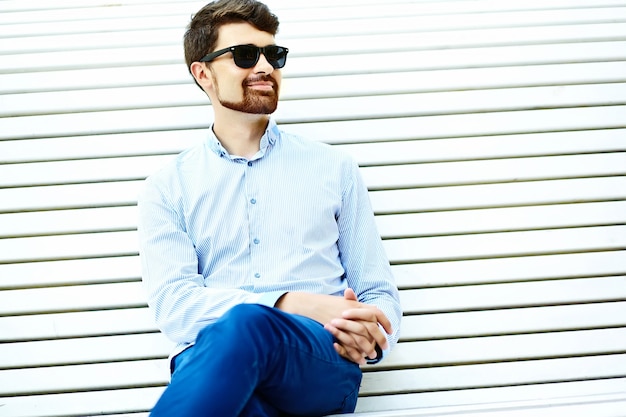 Young handsome hipster Male Student Sitting on the Bench in a Park