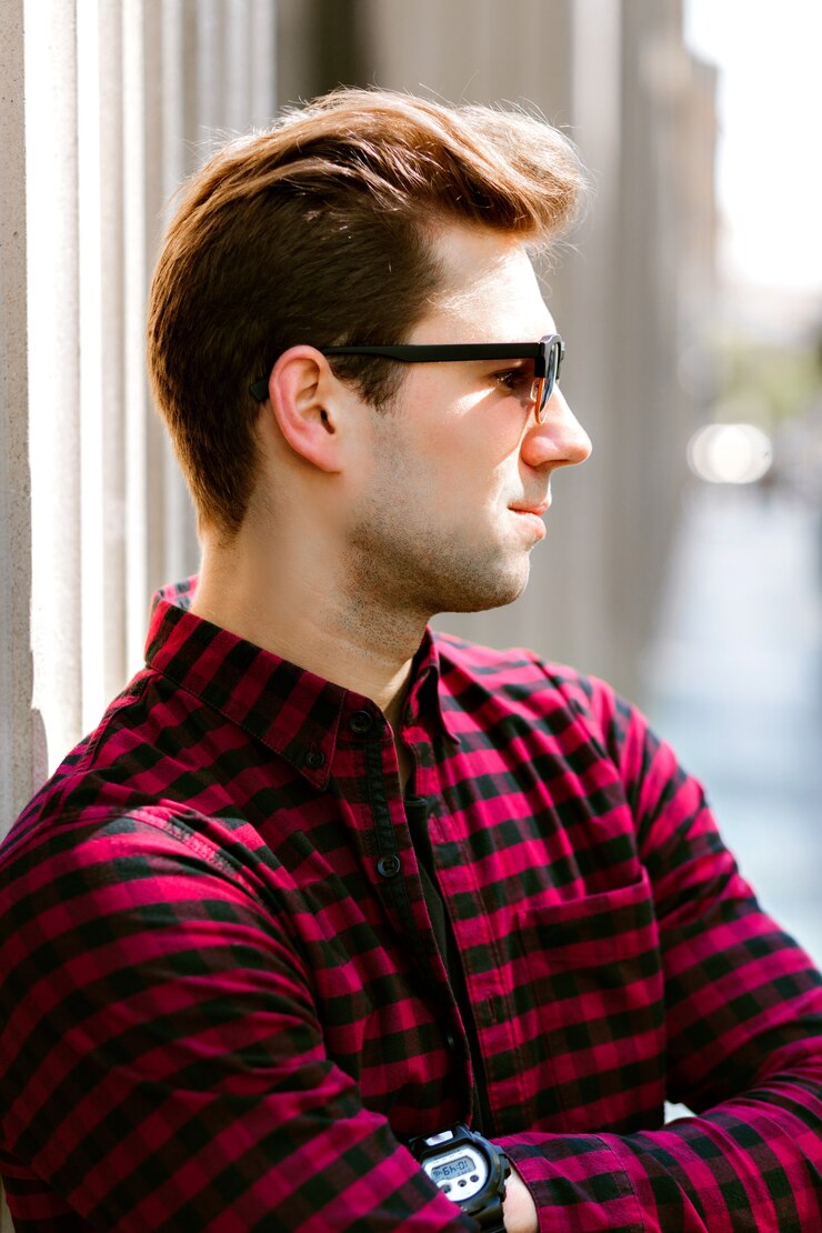 Free Photo young handsome hipster man posing in the street, it businessman, plaid shirt sunglasses, europe city center.