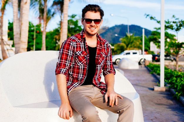 Free photo young handsome hipster man relaxed at sunny day on island park