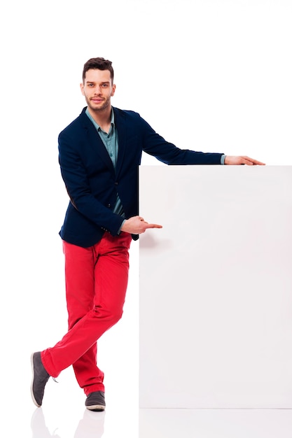 Young and handsome male pointing at blank billboard