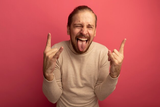 Young handsome man in beige turtleneck crazy happy making rock symbol 