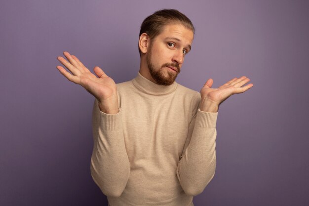 Young handsome man in beige turtleneck looking at front confused and clueless with open arms standing over lilac wall