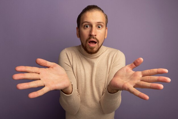 Young handsome man in beige turtleneck looking at front confused standing over lilac wall