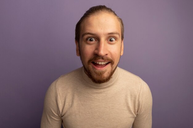 Young handsome man in beige turtleneck surprised and happy 