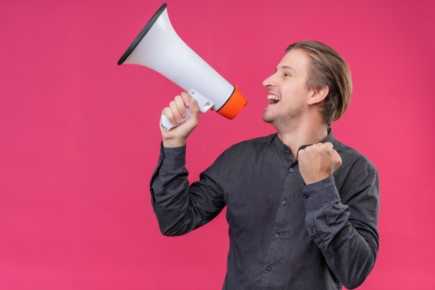 Young handsome man in black shirt shouting to megaphone