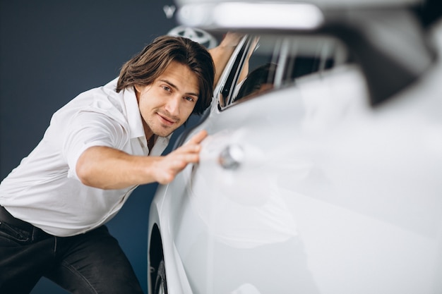 車のショールームで車を選ぶ若いハンサムな男