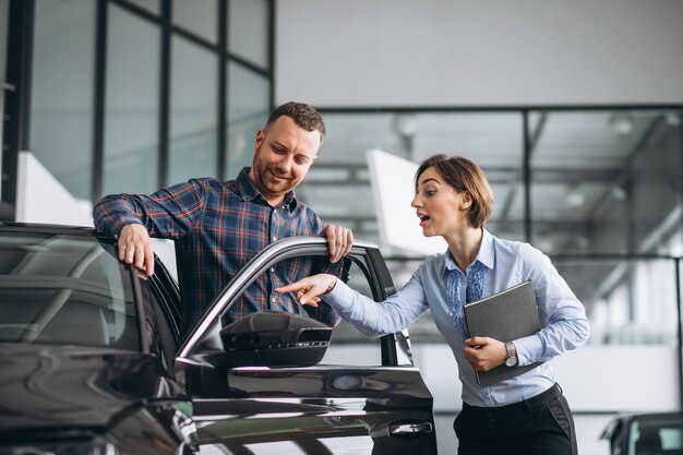 Young handsome man choosing a car in a car showroom