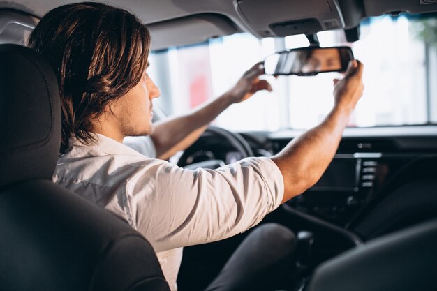 車のショールームで車を選ぶ若いハンサムな男