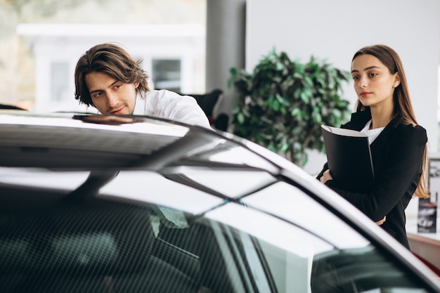 Young handsome man choosing a car in a car showroom