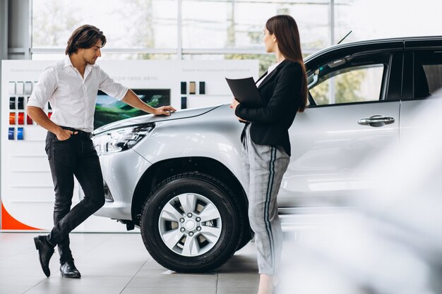 Young handsome man choosing a car in a car showroom