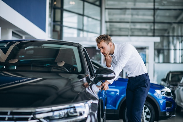 Free photo young handsome man choosing a car in a car showroom