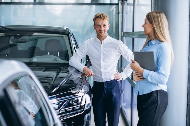 Young handsome man choosing a car in a car showroom