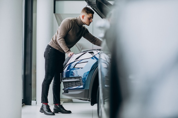 Young handsome man choosing a car in a car showroom