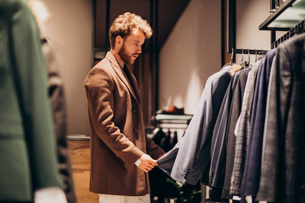 Young handsome man choosing cloth at shop