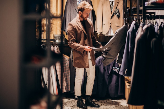 Young handsome man choosing clothes at shop