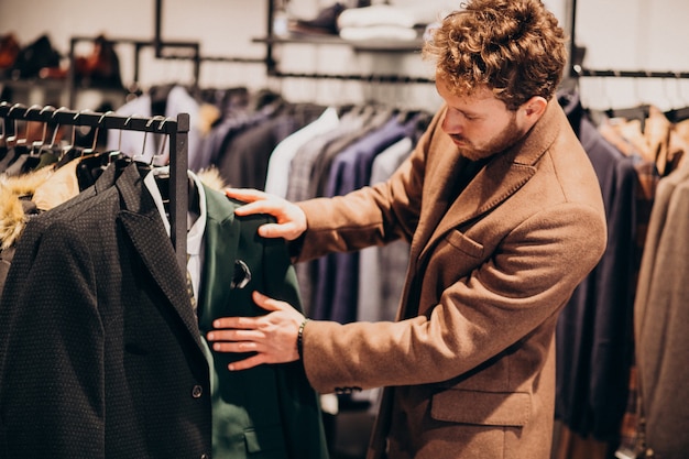 Free photo young handsome man choosing clothes at shop