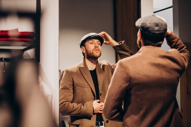 Free photo young handsome man choosing hat at the shop