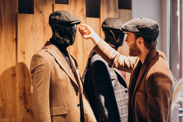 Young handsome man choosing hat at the shop