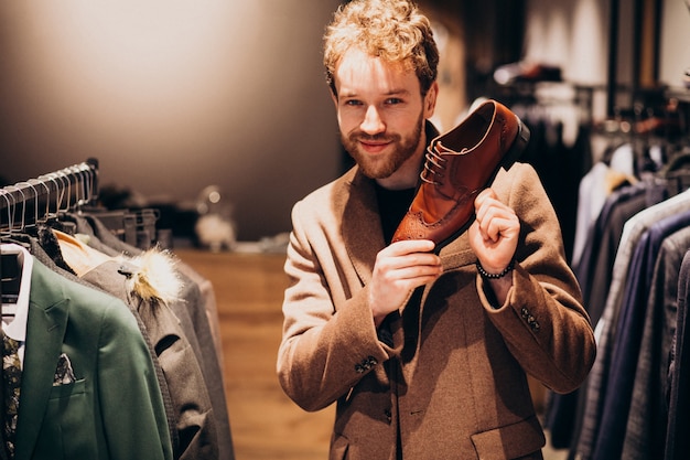 Free photo young handsome man choosing shoes at a shop