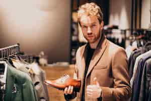 Free photo young handsome man choosing shoes at a shop