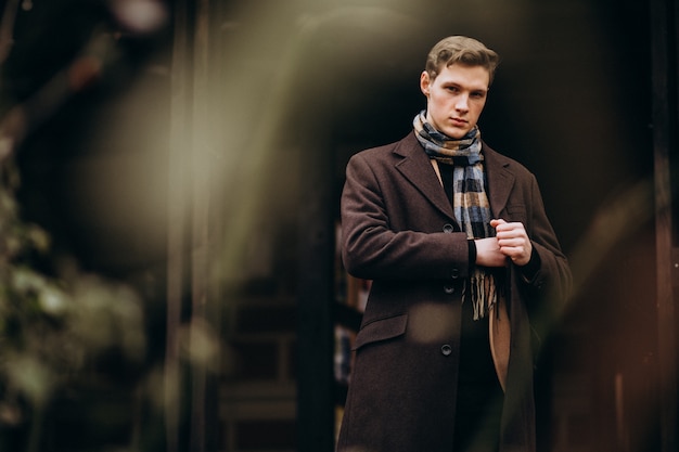 Foto gratuita giovane uomo bello in un cappotto fuori strada