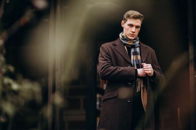 Free photo young handsome man in a coat outside the street