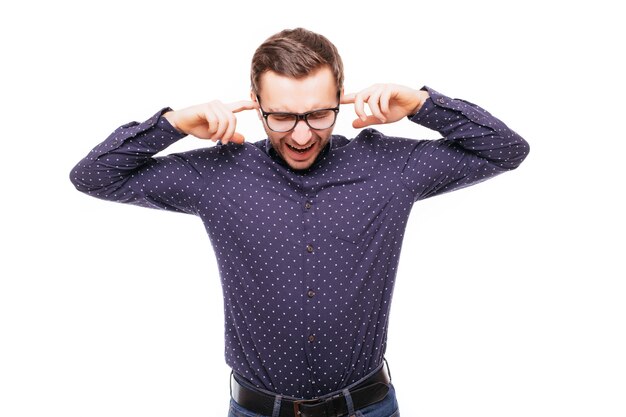 Young handsome man covering his ears ignoring noise on white wall