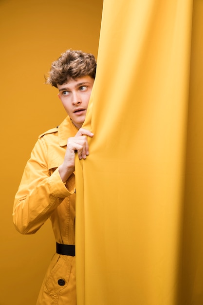 Free Photo | Young handsome man next to a curtain in a yellow scene