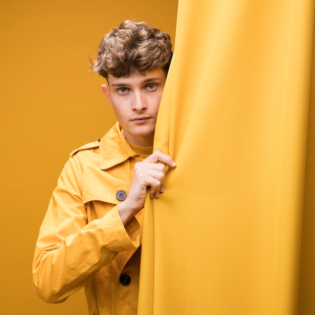 Young handsome man next to a curtain in a yellow scene