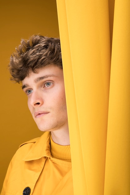 Young handsome man next to a curtain in a yellow scene