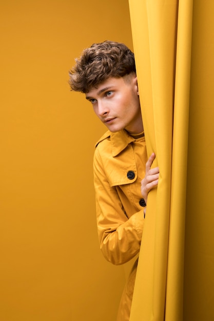 Free photo young handsome man next to a curtain in a yellow scene