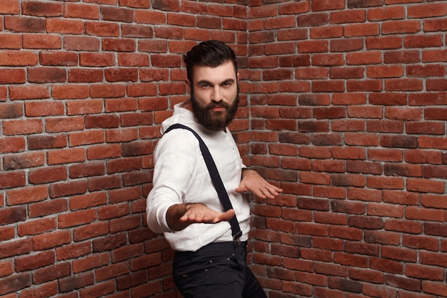 Young handsome man dancing posing on brick wall.