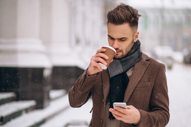 コーヒーを飲みながら電話で話している若いハンサムな男