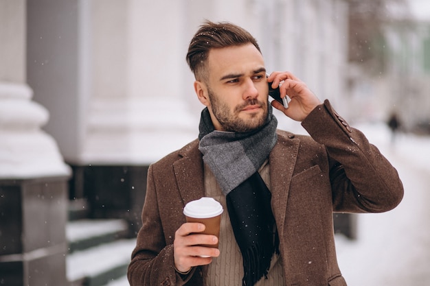 Young handsome man drinking coffee and talking on phone