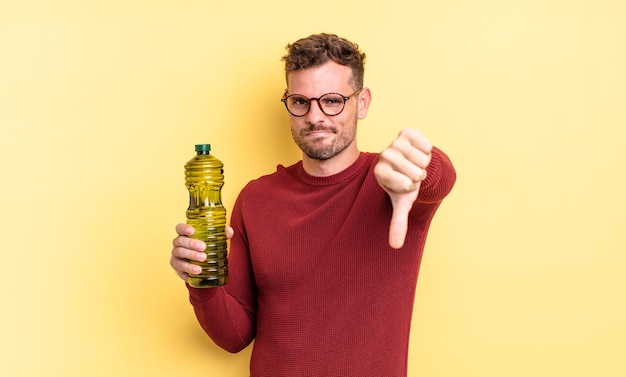 Young handsome man feeling cross,showing thumbs down. olive oil concept