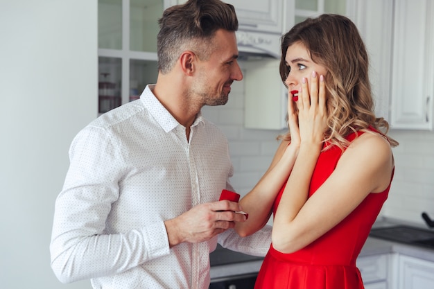 Young handsome man giving an engagement ring to his girlfriend at home