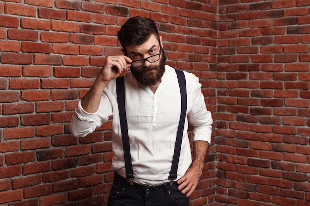 Young handsome man in glasses on brick wall.