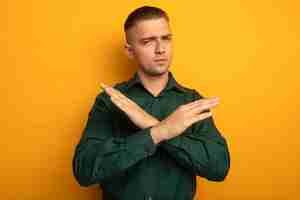 Free photo young handsome man in green shirt making sto gesture crossing arms with serious face