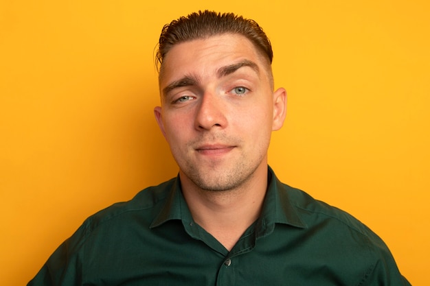 Free photo young handsome man in green shirt smiling with skeptic expression