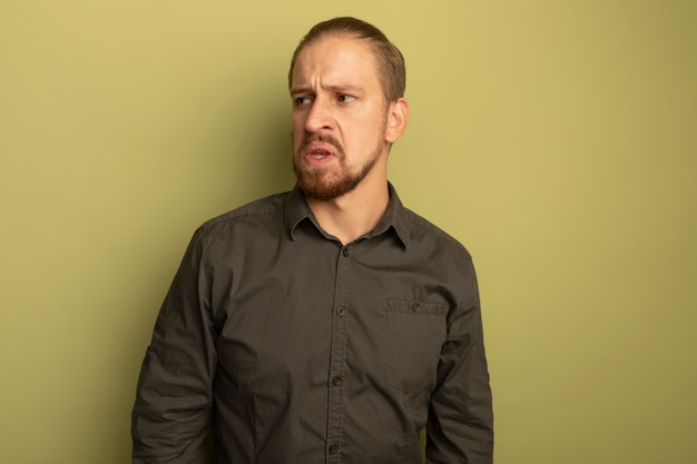 Young handsome man in grey shirt looking aside being displeased and irritated 