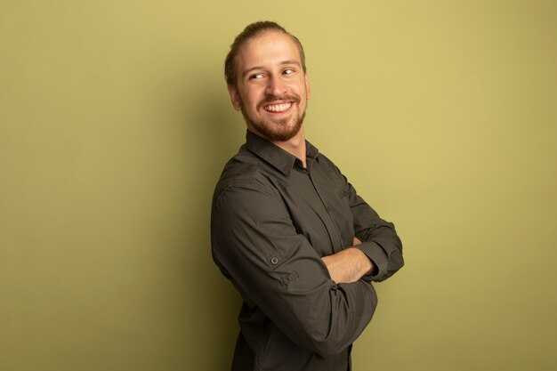 Young handsome man in grey shirt looking aside smiling confident with arms crossed on chest 