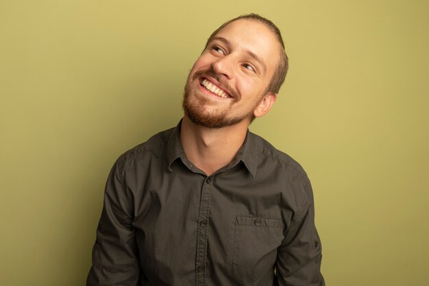 Young handsome man in grey shirt looking up thinking positive smiling broadly 