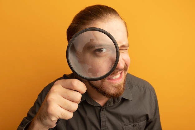 Young handsome man in grey shirt through magnifying glass 