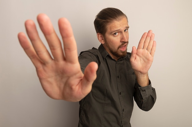 Young handsome man in grey shirt with serious face making stop gesture with open hands 