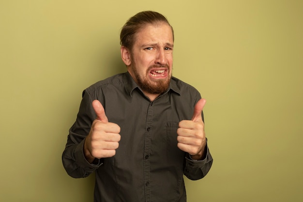 Foto gratuita giovane uomo bello in camicia grigia preoccupato e irritato che mostra i pollici in su