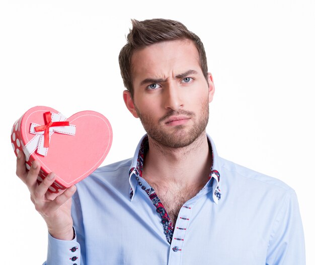 Young handsome man holding a gift and thinking - isolated on white