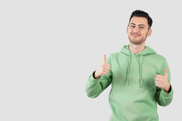 young handsome man in hoodie standing and giving thumbs up