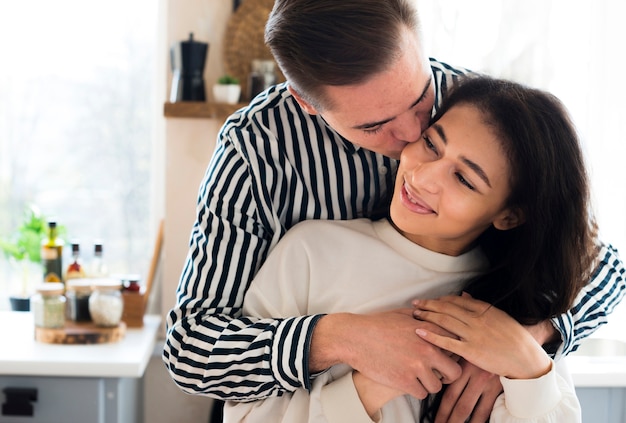 Free photo young handsome man kissing girlfriend on cheek