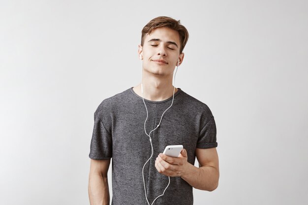 Young handsome man listens music with earphones