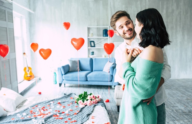 Young handsome man makes a proposal to his beautiful girlfriend to marry him in a beautiful bedroom with a romantic background. husband and wife